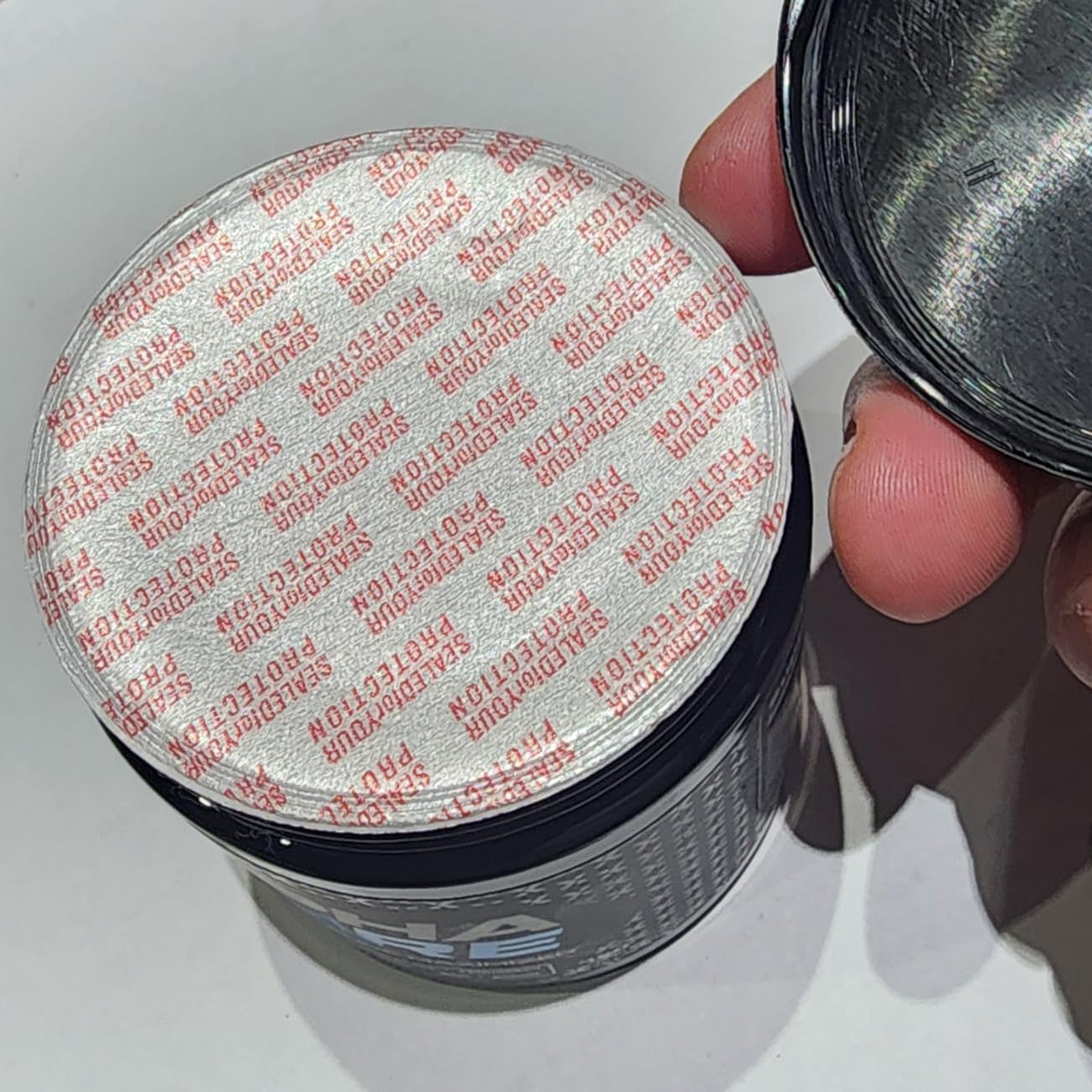 Person holding a container lid with 'Norton' branding on a white background